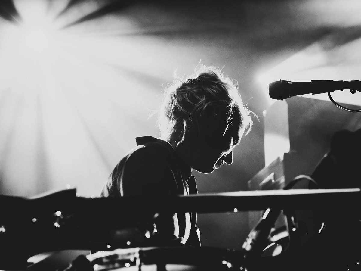 Schwarz-Weiss Aufnahme von Simone Aubert. Im Vodergrund stehen Instrumente, Simone schaut halb abgewandt auf ein weiteres Instrumente.